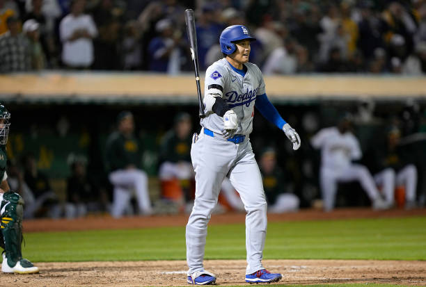Shohei Ohtani of the Los Angeles Dodgers flips his bat after hitting a three-run home run against the Oakland Athletics in the top of the ninth...