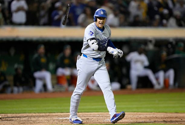 Shohei Ohtani of the Los Angeles Dodgers flips his bat after hitting a three-run home run against the Oakland Athletics in the top of the ninth...