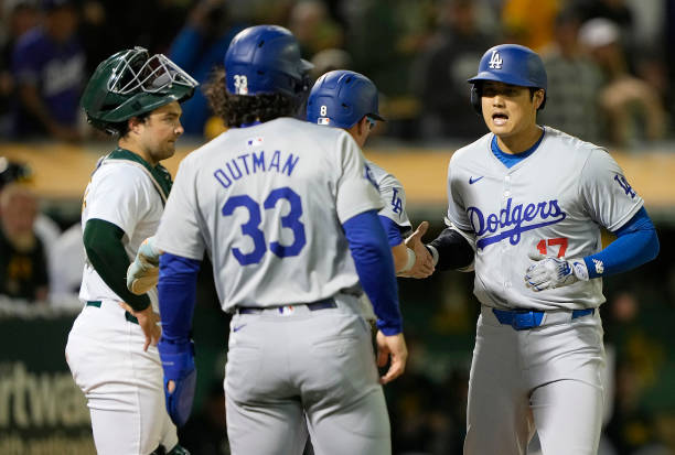 Shohei Ohtani of the Los Angeles Dodgers is congratulated by Enrique Hernández and James Outman after Ohtani hit a three-run home run against the...