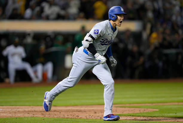 Shohei Ohtani of the Los Angeles Dodgers reacts after hitting a three-run home run against the Oakland Athletics in the top of the ninth inning at...