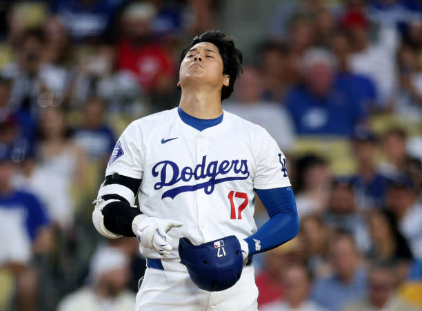 Shohei Ohtani of the Los Angeles Dodgers reacts as he adjusts his helmet during the third inning against the Philadelphia Phillies at Dodger Stadium...