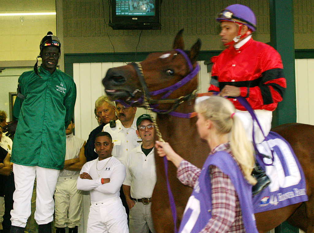former-nba-star-manute-bol-watches-a-horse-and-jockey-pass-him-before-picture-id2614076