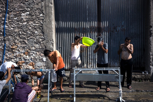 People wash their hands, faces and body at the port of Piraeus, where nearly 1,500 refugees and migrants live at a makeshift camp or in passenger areas, in Athens on July 3, 2016