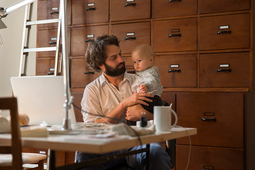 Young designer with baby son in home office : Stock Photo