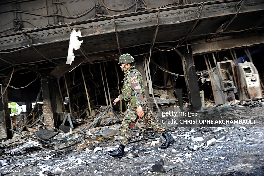 A soldier walks past burnt shops after g