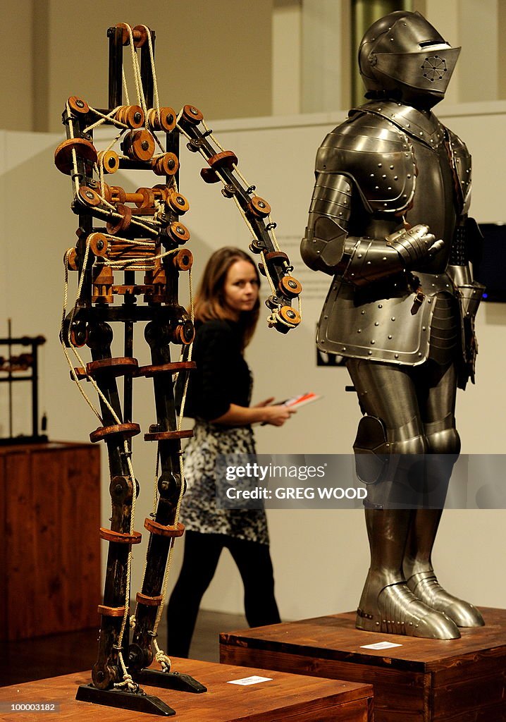 A woman (C) walks past robotic models wh