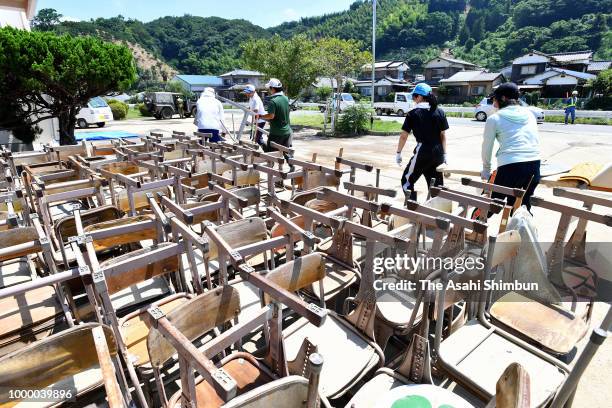 Volunteer workers remove damaged desk and chairs from Yoshida Junior High School on July 14, 2018 in Uwajima, Ehime, Japan. More than 100 people were...