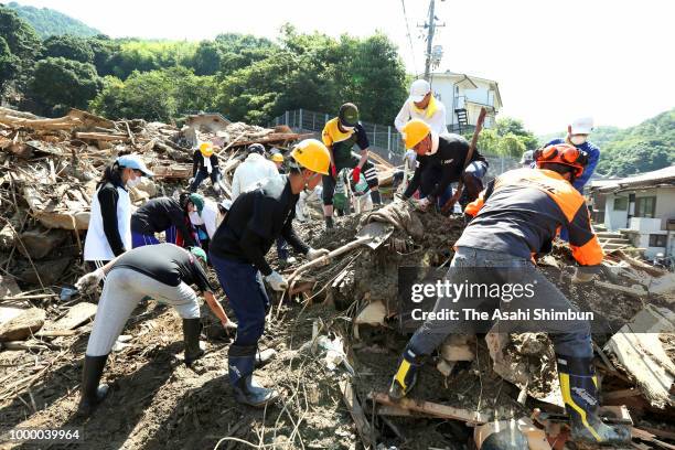 Volunteer workers remove debris at a landslide site on July 14, 2018 in Kure, Hiroshima, Japan. More than 100 people were treated for heatstroke as...