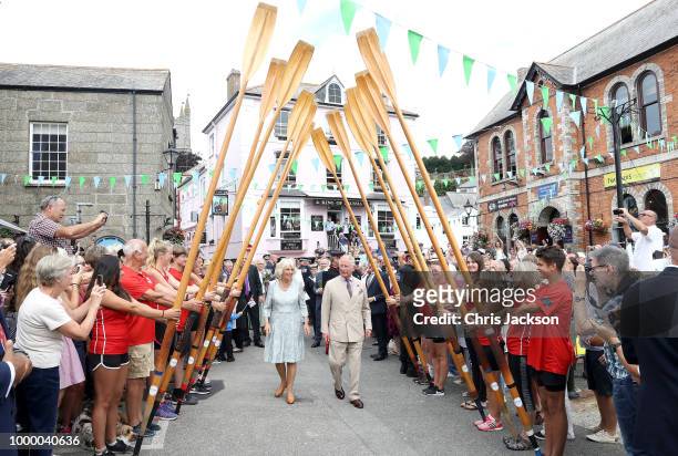 Camilla, Duchess Of Cornwall and Prince Charles, Prince Of Wales walk through a guard of honour by representatives from the Fowey Gig Club as they...