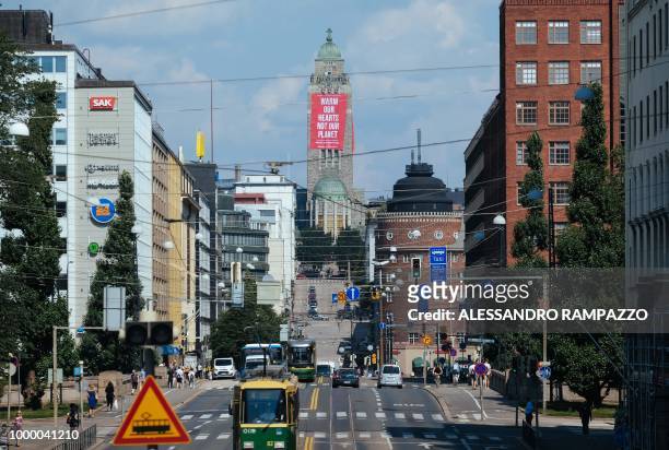 Banner reading "Warm our Hearts not our planet" by environmental NGO Greenpeace is fixed at the Kallio Church tower in Helsinki, Finland, on July 16,...