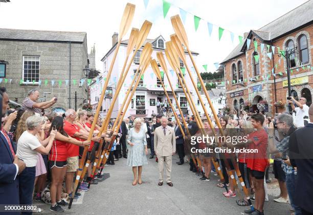 Camilla, Duchess Of Cornwall and Prince Charles, Prince Of Wales walk through a guard of honour by representatives from the Fowey Gig Club as they...