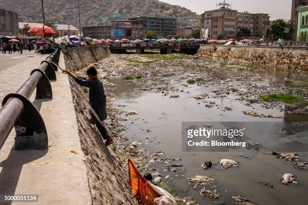 Pickers climb a riverbank with sacks of recyclable materials collected from the Kabul River in Kabul, Afghanistan, on Thursday, July 12, 2018. U.S...