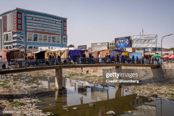 Pedestrians walk along a footbridge over the Kabul River in Kabul, Afghanistan, on Thursday, July 12, 2018. U.S President Donald last year said...