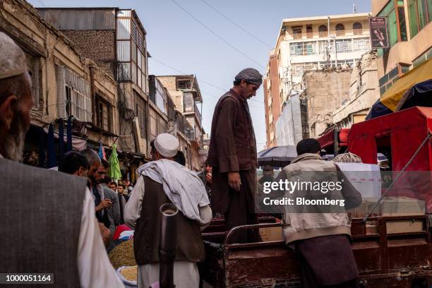 Pedestrians and traders walk past a man standing on the back of a pick up vehicle at Mandai Bazaar in Kabul, Afghanistan, on Thursday, July 12, 2018....