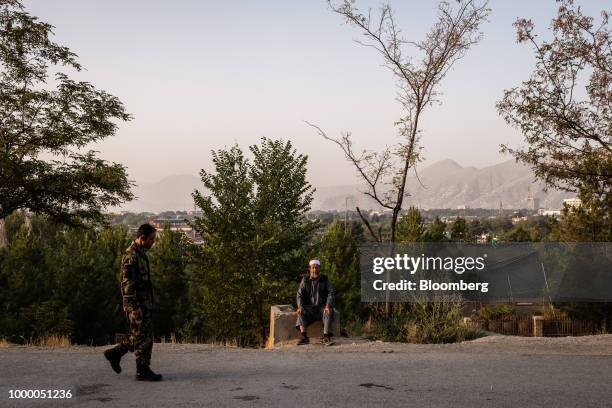 An Afghan soldier walks pat a man sitting on the side of the road in the Bibi Mahru Hill area of Kabul, Afghanistan, on Sunday, July 15, 2018. U.S...