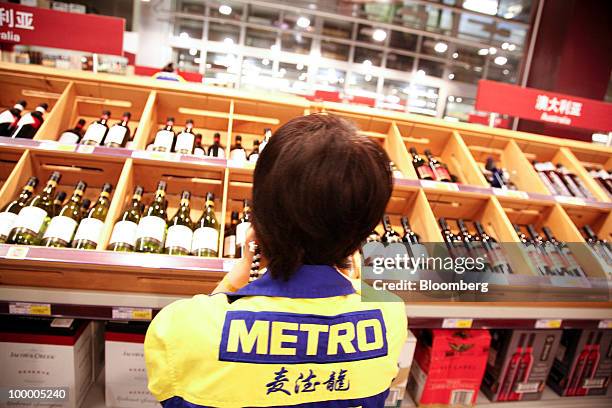 Staff member works in the wine department at a Metro AG supermarket in Shanghai, China, on Wednesday, May 19, 2010. Metro AG, Germany's largest...