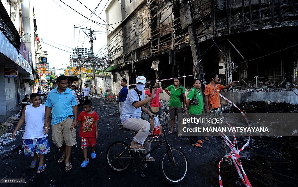 People gather in front of a burnt buildi