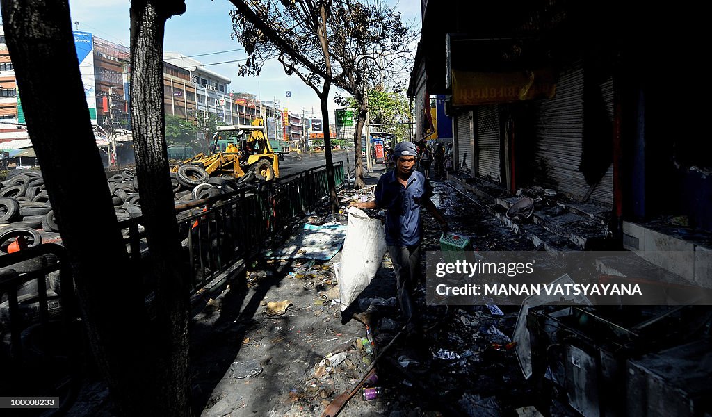 A Thai worker removes debris in front of