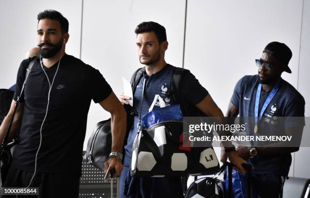 France's defender Adil Rami, goalkeeper Hugo Lloris and defender Samuel Umtiti depart home from Moscow's Sheremetyevo airport on July 16 after...