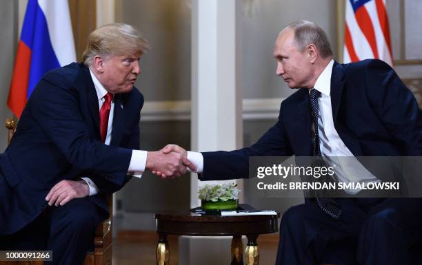 Russian President Vladimir Putin and US President Donald Trump shake hands before a meeting in Helsinki, on July 16, 2018.