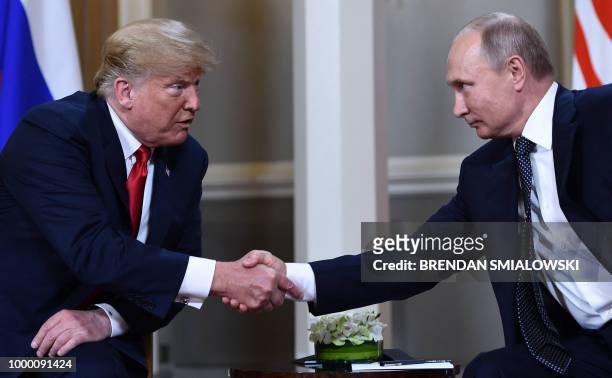 Russian President Vladimir Putin and US President Donald Trump shake hands before a meeting in Helsinki, on July 16, 2018.
