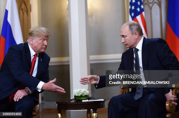 President Donald Trump and Russian President Vladimir Putin reach to shake hands before a meeting in Helsinki, on July 16, 2018.