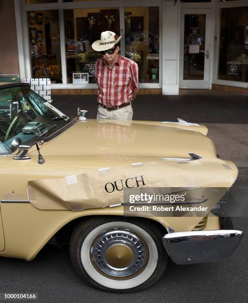 An 'Ouch' sign covers damage from a recent accident on a 1950s Plymouth on display at a classic car show in Santa Fe, New Mexico.