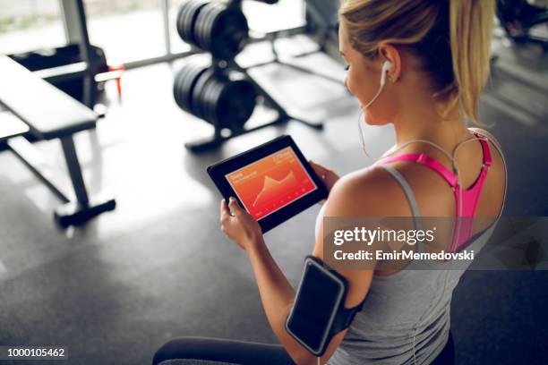 tracking her progress with fitness app on digital tablet - personal training stock pictures, royalty-free photos & images