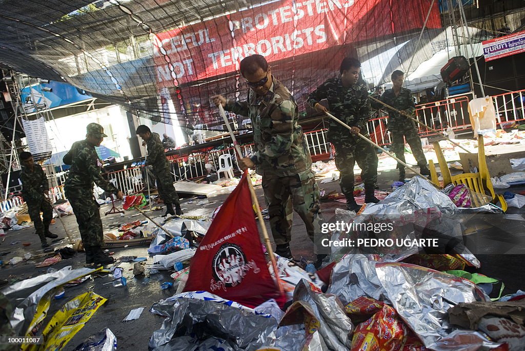 A Thai soldier uses a red flag to clean