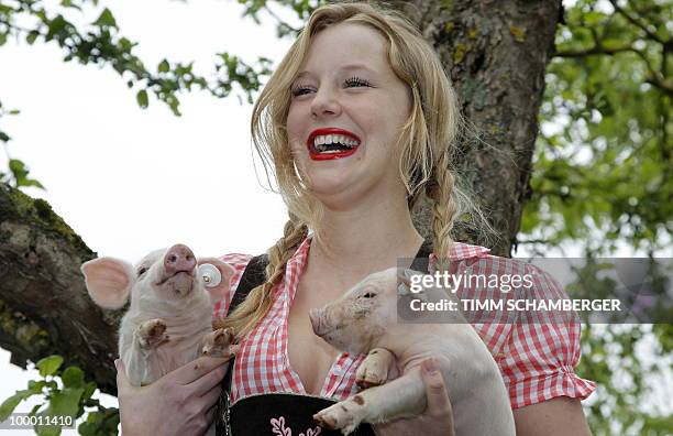 Model Jasmin poses with two piglets during a photocall to promote the "Young Farmers Calendar 2011" on a farm in Schraudenbach, southern Germany, on...