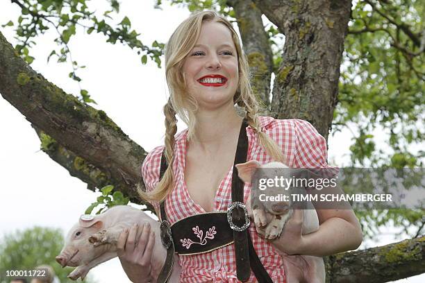 Model Jasmin poses with two piglets during a photocall to promote the "Young Farmers Calendar 2011" on a farm in Schraudenbach, southern Germany, on...