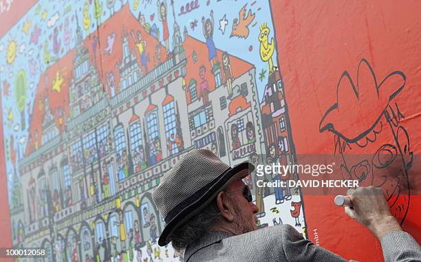 Pop-artist James Rizzi paints on a poster designed by him during a press preview of the exhibition "Rizzi's World" on May 20, 2010 in Bremen,...