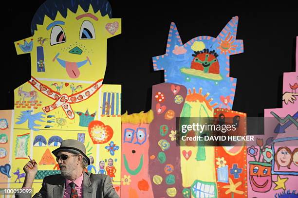 Pop-artist James Rizzi sits in front of paintings by children from Bremen as he gives an interview on the exhibition "Rizzi's World" on May 20, 2010...