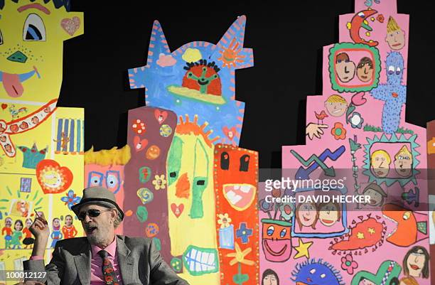 Pop-artist James Rizzi sits in front of paintings by children from Bremen as he gives an interview on the exhibition "Rizzi's World" on May 20, 2010...