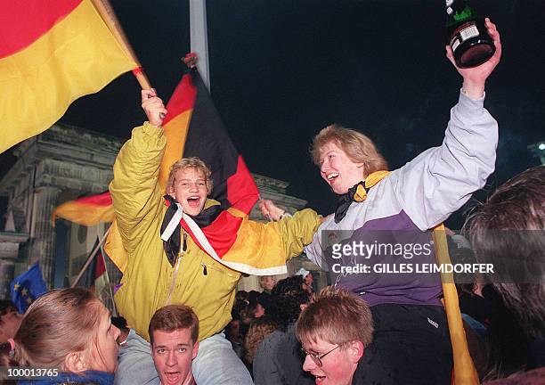 Berlin youths wave German flags during celebrationa of the country's reunification, at the Brandenburg Gate in Berlin 03 October 1990. Forty-five...