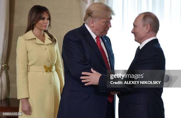 President Donald Trump shakes hands with Russia's President Vladimir Putin next to US First Lady Melania Trump ahead a meeting in Helsinki, on July...