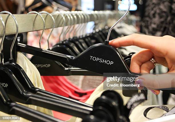 Shopper selects an item of clothing at a Topshop retail store in London, U.K., on Thursday, May 20, 2010. Sir Philip Green, the billionaire owner of...