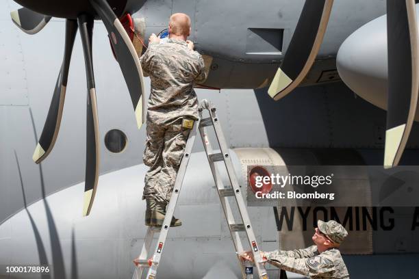 An attendee in military uniform places a sticker on a C-130H Hercules turboprop military transport aircraft on the opening day of the Farnborough...