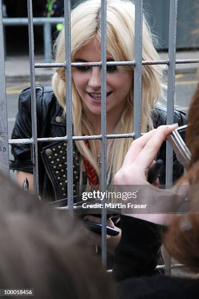 Pixie Lott smiles, waves and signs autographs through a metal fence for her Scottish fans on the other side of it, at the SECC where she is...