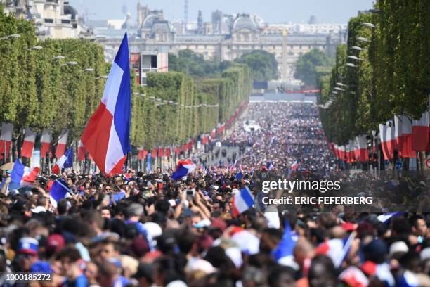 Supporters wave French national flags while they gather on the Champs-Elysees avenue in Paris on July 16, 2018 as they wait for the arrival of the...