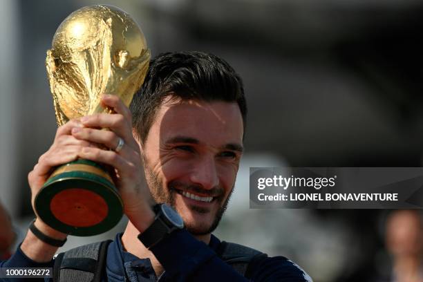 France's goalkeeper Hugo Lloris smiles as he holds the trophy as he celebrates with teammates upon their arrival at the Roissy-Charles de Gaulle...