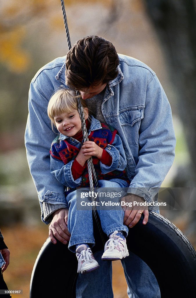 FATHER & DAUGHTER PLAYING ON TIRE SWING