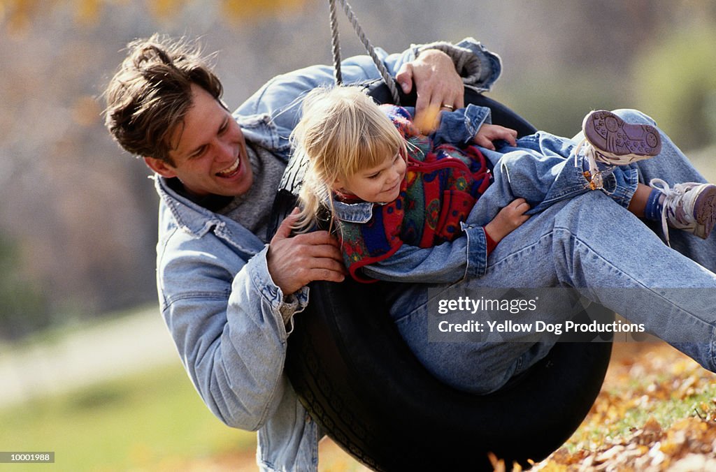 FATHER & DAUGHTER PLAYING ON TIRE SWING