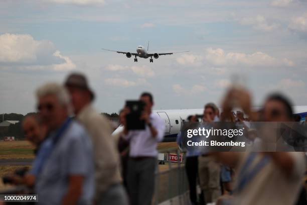 Spectators watch the flying display as an aircraft comes into land on the opening day of the Farnborough International Airshow 2018 in Farnborough,...