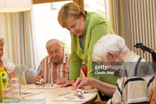 German Chancellor Angela Merkel speaks with elderly during a visit to the St. Johannesstift senior care facility on July 16, 2018 in Paderborn,...