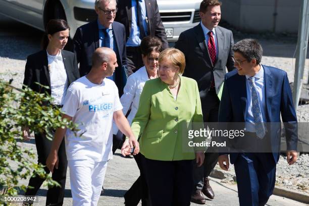 German Chancellor Angela Merkel speaks with Ferdi Cebi , a caregiver at the St. Johannesstift senior care facility, during a visit on July 16, 2018...