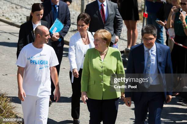 German Chancellor Angela Merkel speaks with Ferdi Cebi, a caregiver at the St. Johannesstift senior care facility, during a visit on July 16, 2018 in...