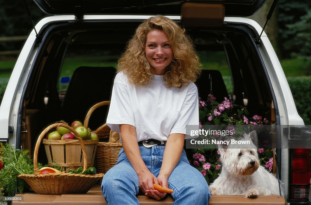 WOMAN SITTING ON TAILGATE WITH DOG