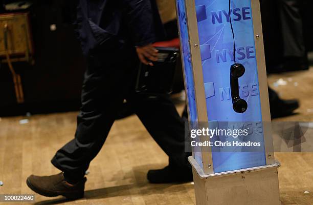 Financial professional walks past a phone left off the hook on the floor of the New York Stock Exchange near the end of the trading day May 20, 2010...