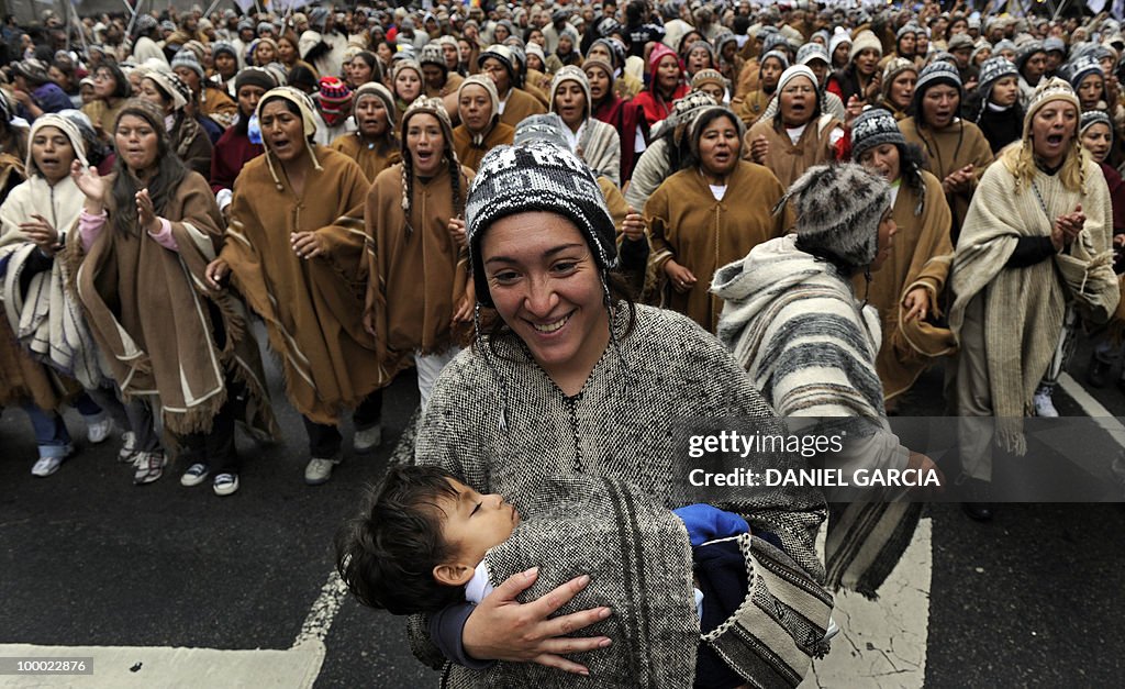 A mother carries her son as thousands of